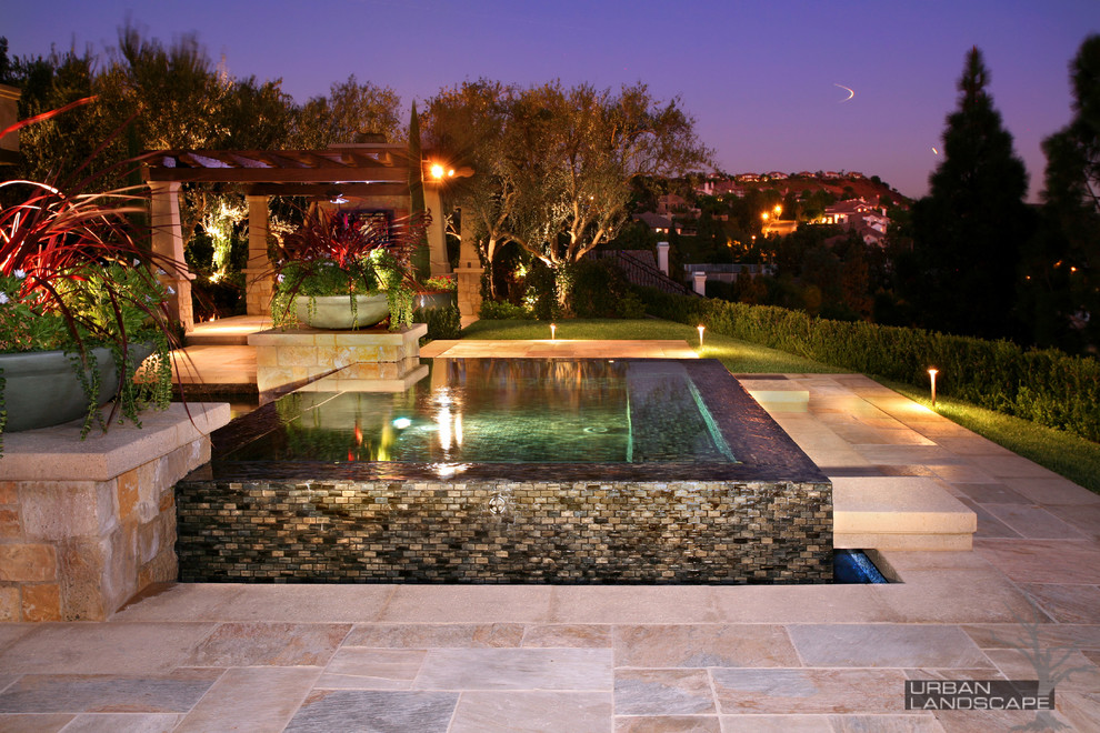 Hot tub - large mediterranean backyard stone and rectangular infinity hot tub idea in Orange County