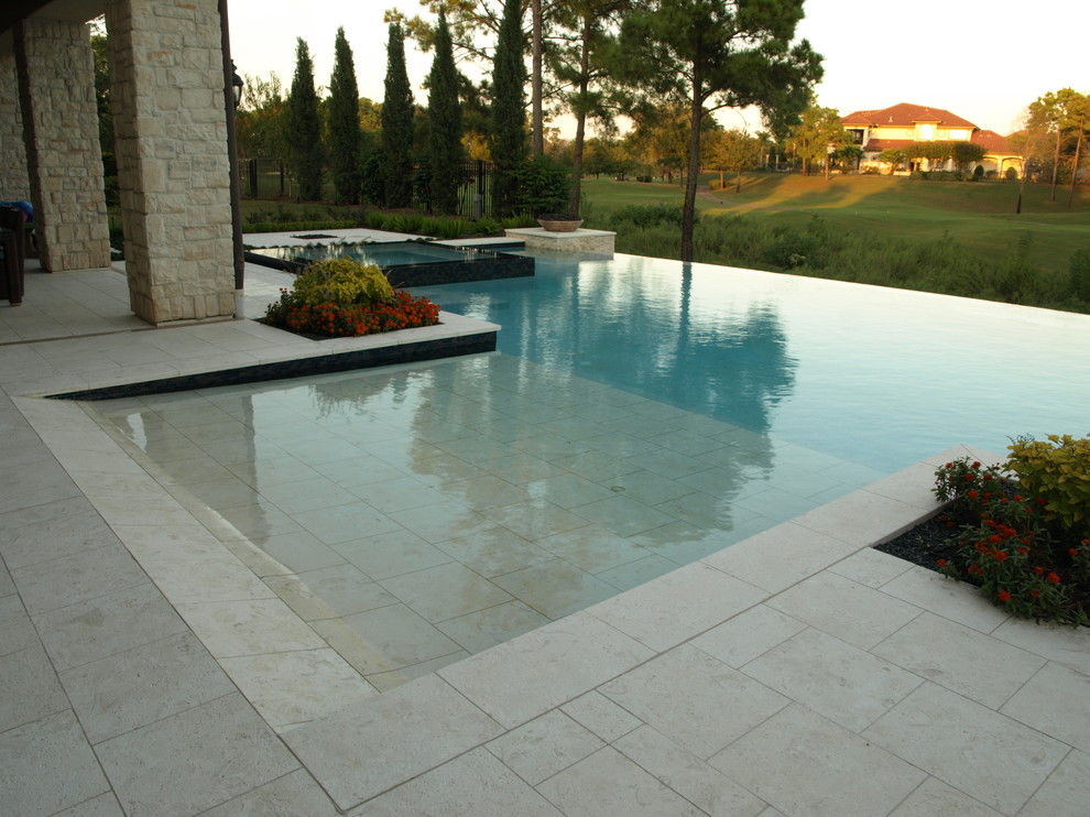 Ejemplo de piscinas y jacuzzis infinitos actuales grandes a medida en patio trasero con suelo de baldosas