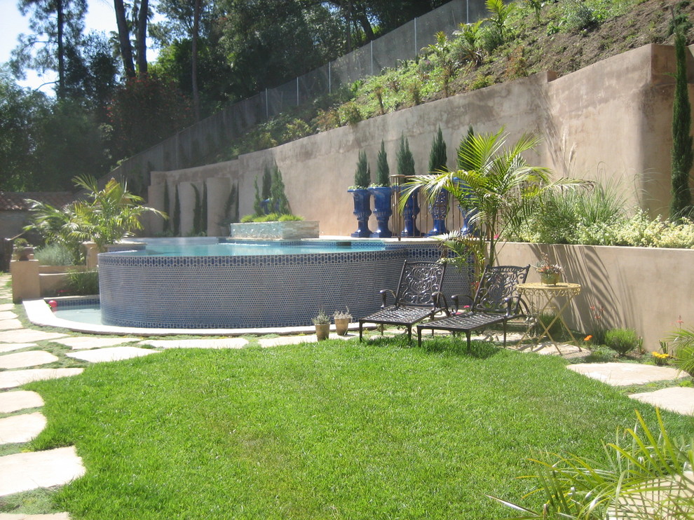 Ejemplo de piscina con fuente infinita rural grande a medida en patio trasero con adoquines de piedra natural