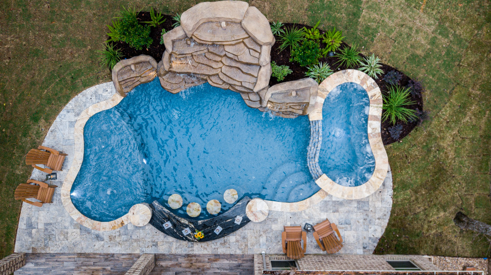 Cette photo montre une grande piscine arrière exotique sur mesure avec des pavés en pierre naturelle.
