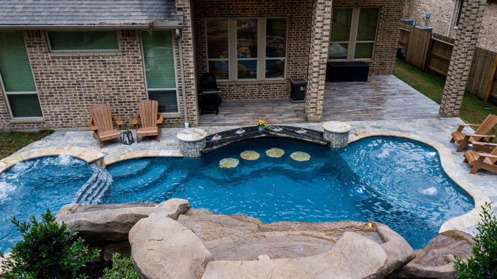 Foto di una grande piscina tropicale personalizzata dietro casa con pavimentazioni in pietra naturale