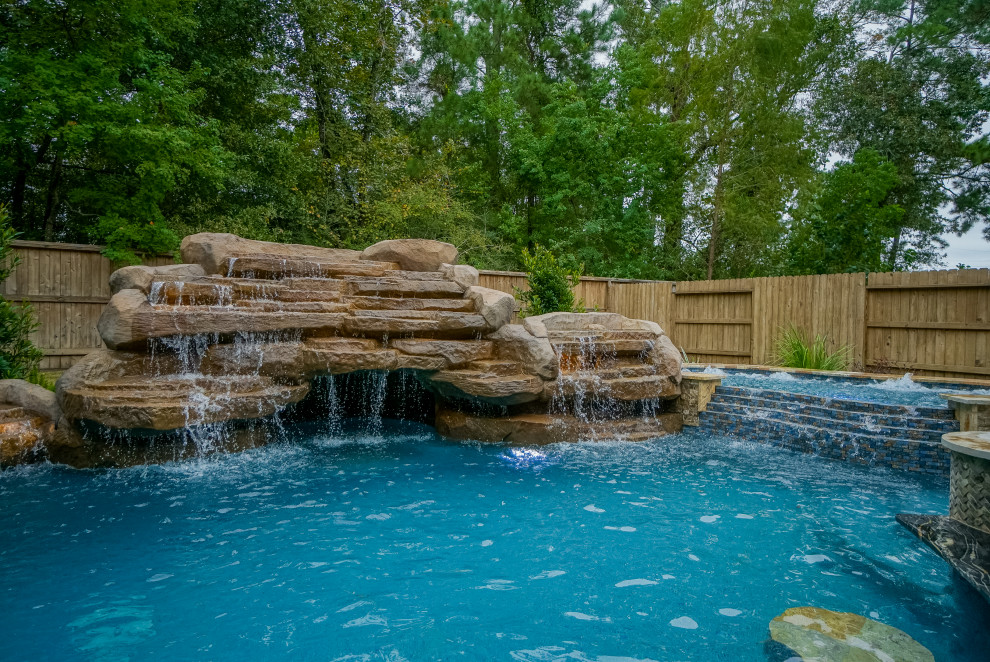 Ispirazione per una grande piscina tropicale personalizzata dietro casa con pavimentazioni in pietra naturale