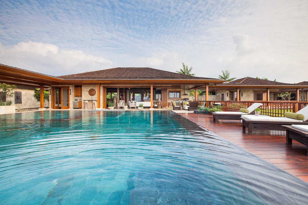 Large world-inspired back rectangular infinity swimming pool in Hawaii with decking.