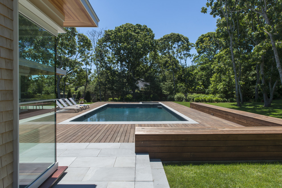 Modelo de piscina alargada actual rectangular en patio trasero con entablado