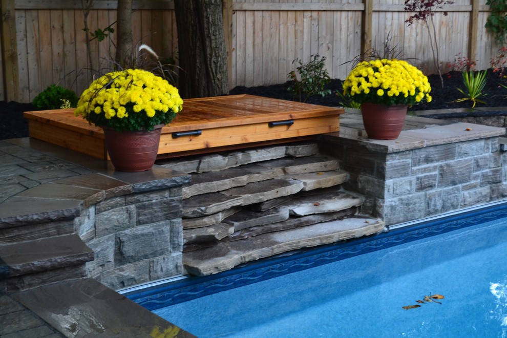 This is an example of a large contemporary back custom shaped lengths swimming pool in Toronto with a water feature and concrete paving.