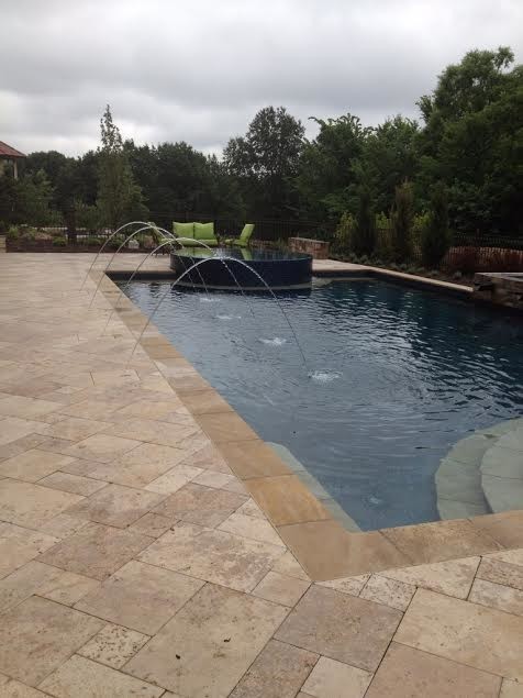 Design ideas for a large classic back rectangular swimming pool in Kansas City with a water feature and natural stone paving.