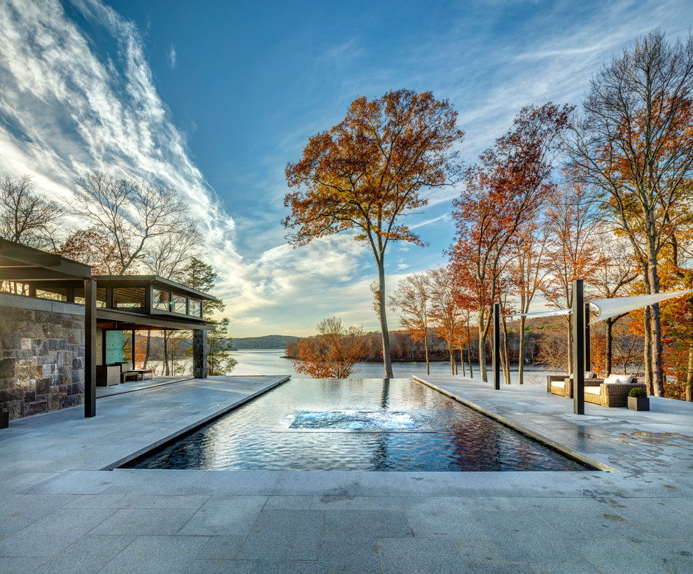 Immagine di una grande piscina a sfioro infinito minimal rettangolare dietro casa con una vasca idromassaggio e piastrelle