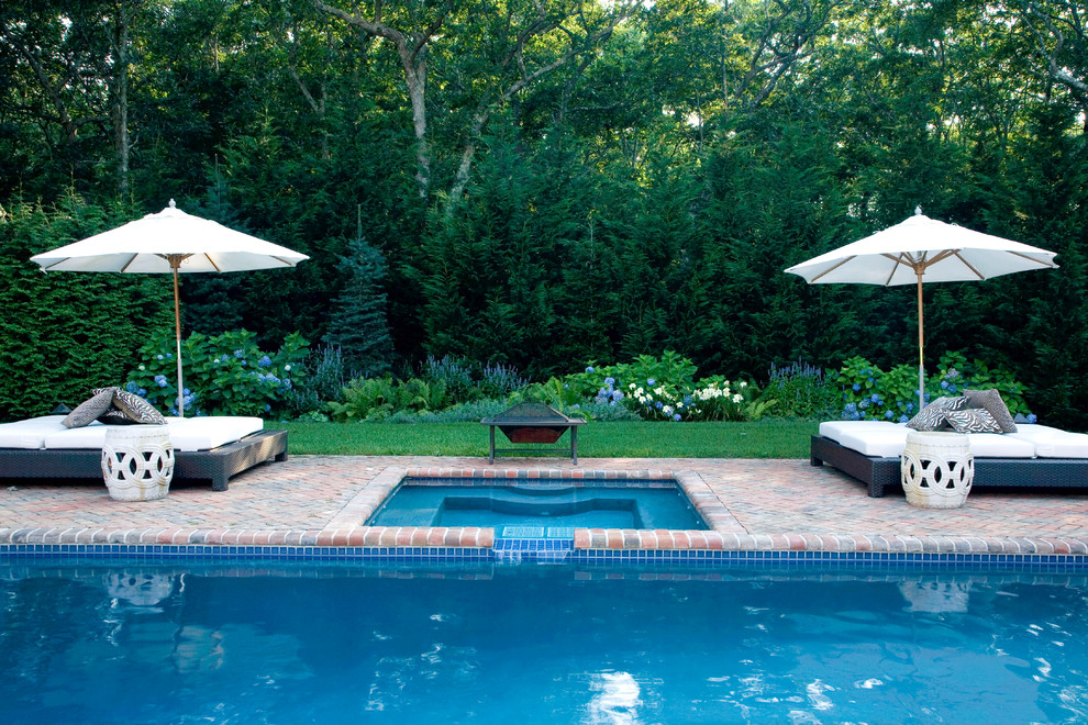Immagine di una piscina classica rettangolare con pavimentazioni in mattoni e una vasca idromassaggio