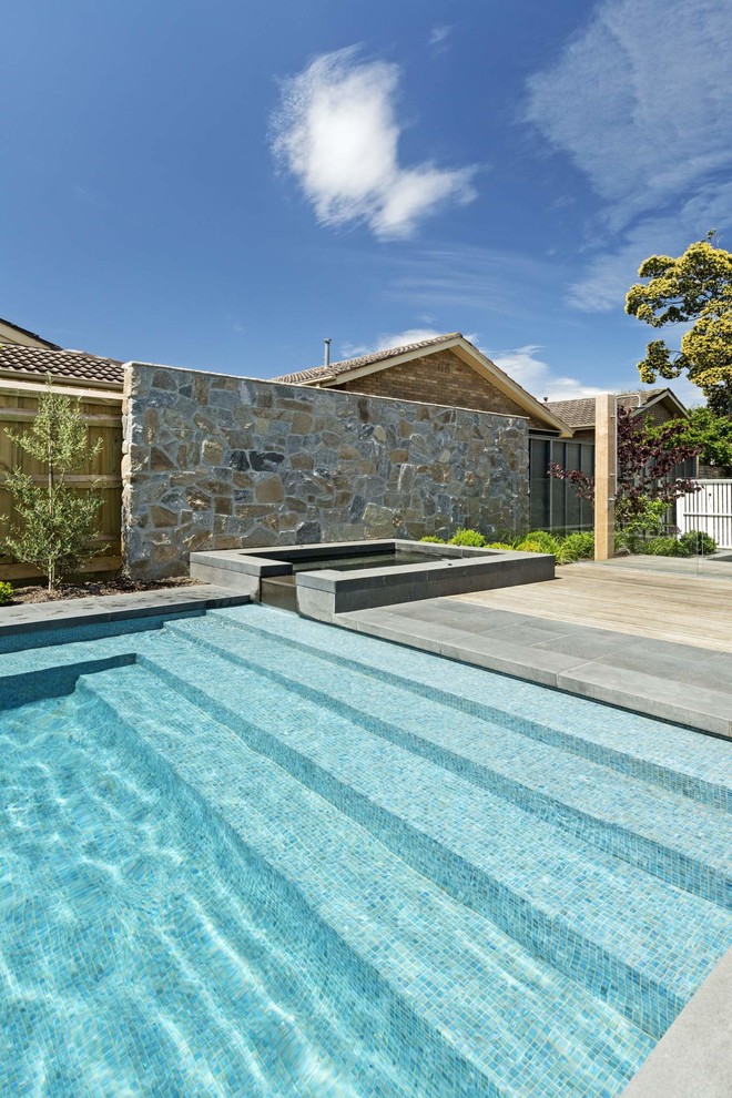 Пример оригинального дизайна: прямоугольный бассейн на заднем дворе в современном стиле с джакузи и мощением тротуарной плиткой