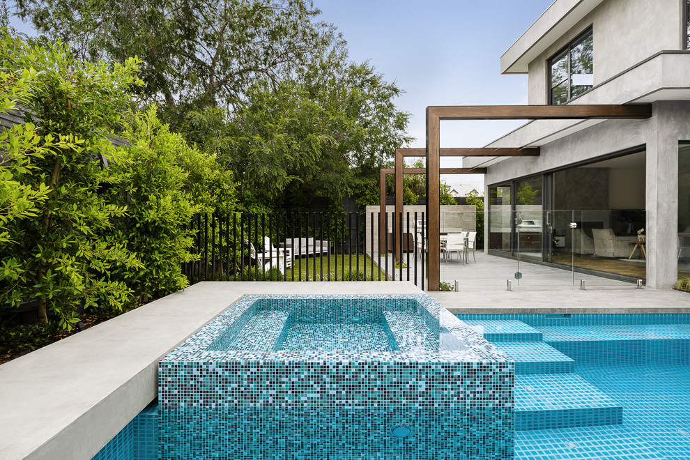 Стильный дизайн: большой прямоугольный бассейн-инфинити на заднем дворе в современном стиле с покрытием из бетонных плит - последний тренд
