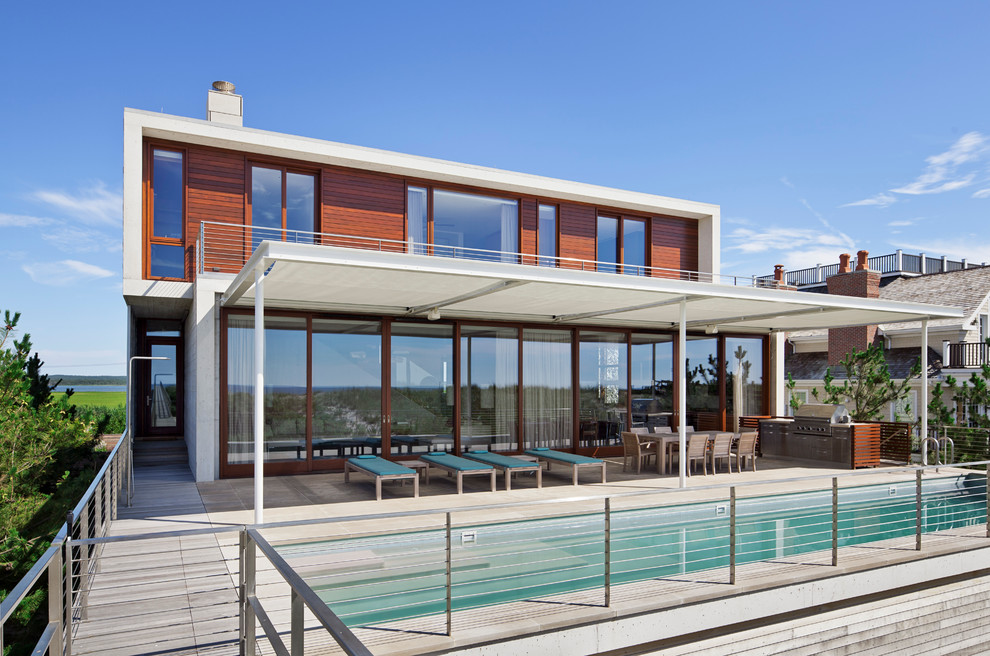 Стильный дизайн: прямоугольный, спортивный бассейн на заднем дворе в морском стиле с покрытием из бетонных плит и зоной барбекю - последний тренд