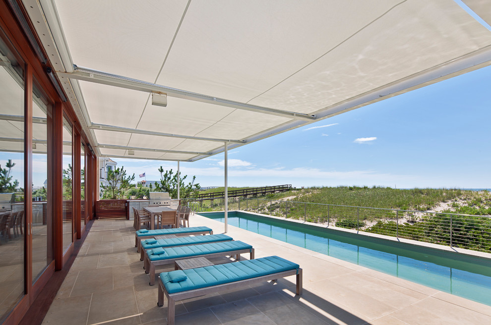 Imagen de piscina alargada costera rectangular en patio trasero con losas de hormigón