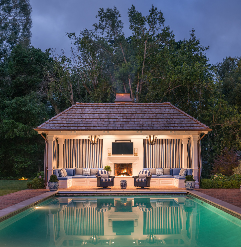 Ejemplo de piscina tradicional grande rectangular en patio trasero con adoquines de ladrillo