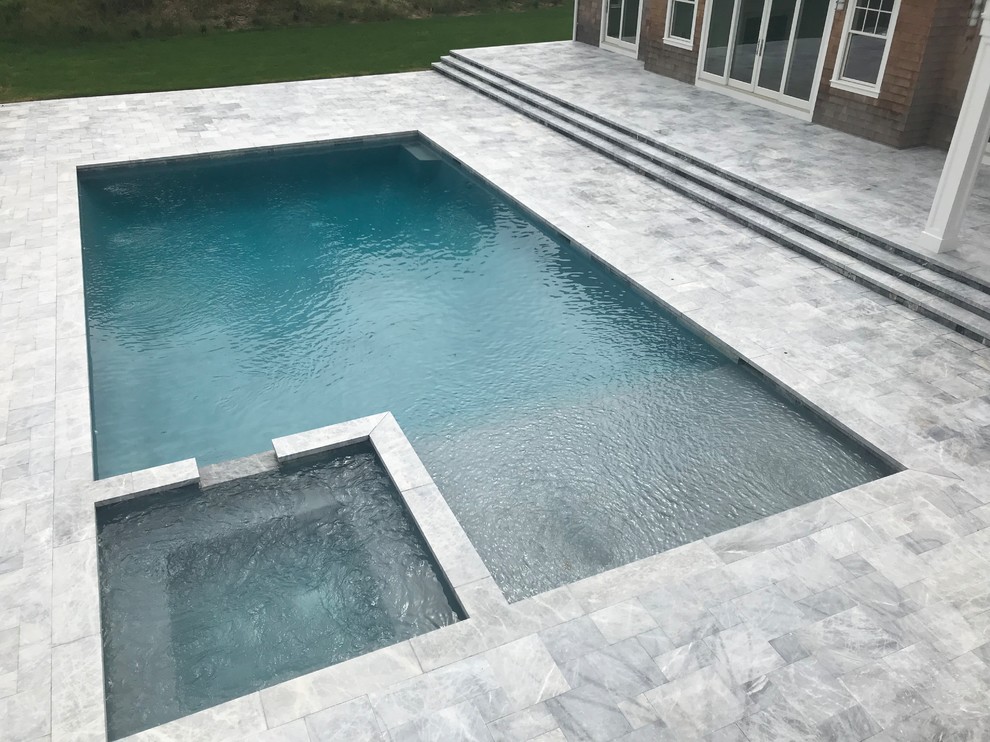 Diseño de piscinas y jacuzzis alargados actuales extra grandes rectangulares en patio trasero con adoquines de piedra natural