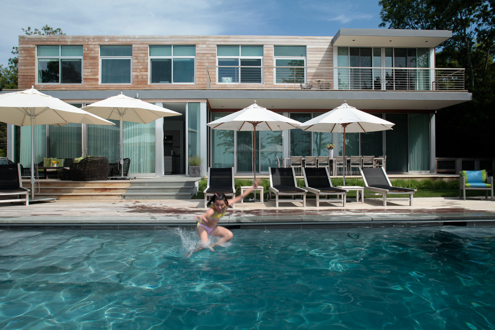 Ejemplo de casa de la piscina y piscina alargada minimalista de tamaño medio a medida en patio trasero con adoquines de hormigón