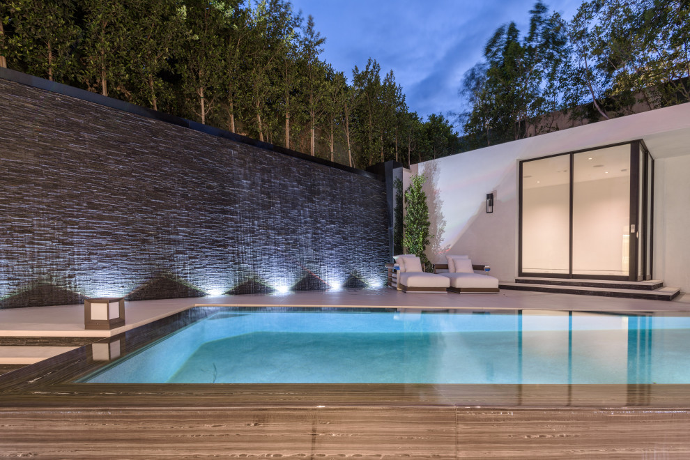 Идея дизайна: прямоугольный бассейн-инфинити среднего размера на заднем дворе в стиле модернизм с домиком у бассейна и покрытием из плитки