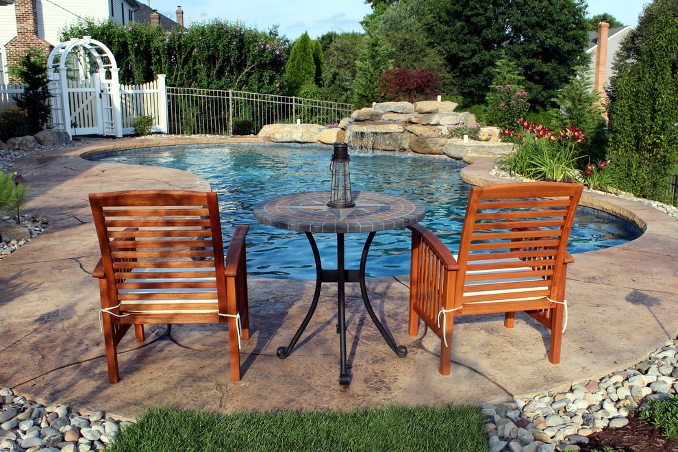На фото: естественный бассейн произвольной формы на заднем дворе в классическом стиле с покрытием из декоративного бетона с