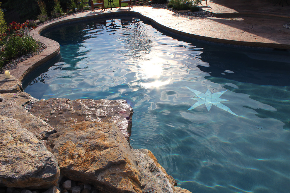 Imagen de piscina natural tradicional a medida en patio trasero con suelo de hormigón estampado