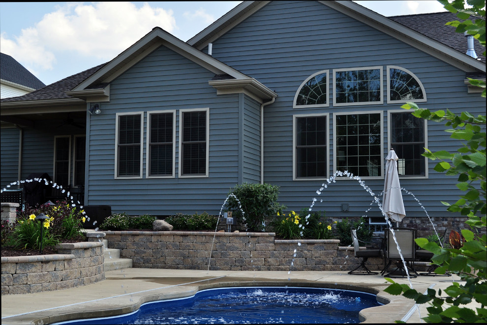 Mid-sized arts and crafts backyard concrete paver and custom-shaped lap pool fountain photo in Cleveland