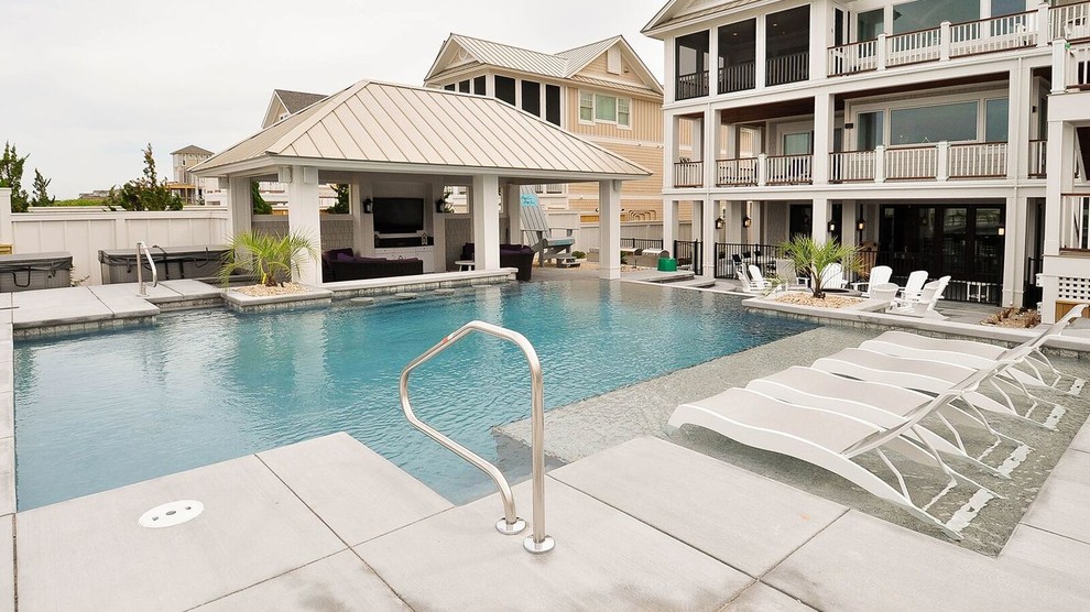 Modelo de casa de la piscina y piscina alargada contemporánea grande rectangular en patio trasero con adoquines de hormigón