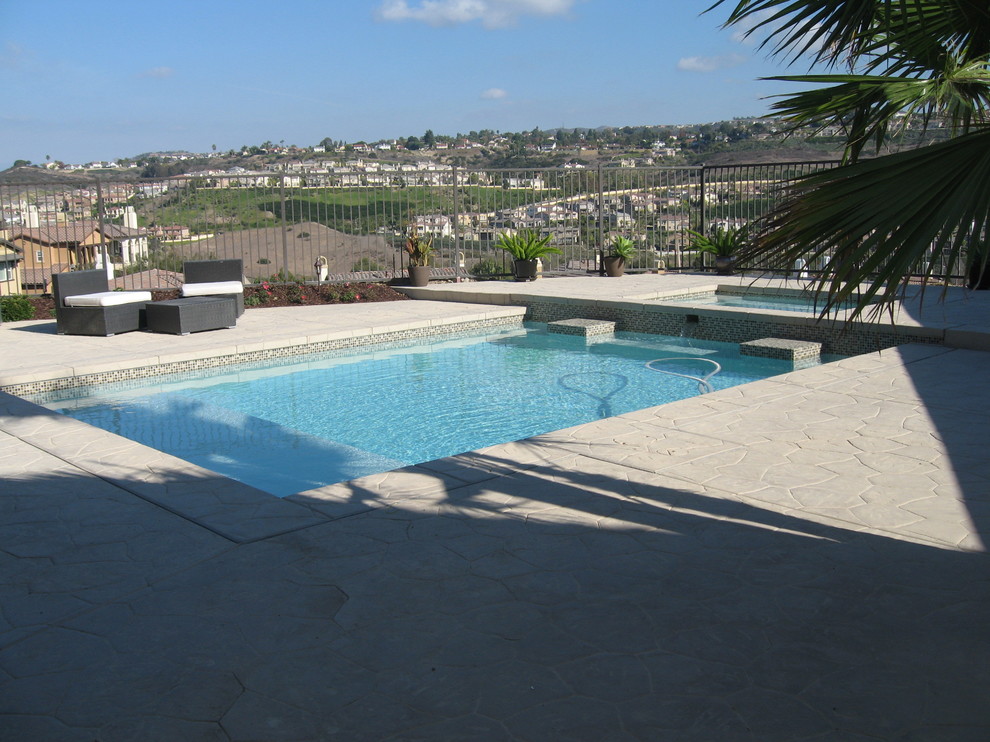 На фото: естественный, прямоугольный бассейн среднего размера на заднем дворе в современном стиле с джакузи и покрытием из декоративного бетона с