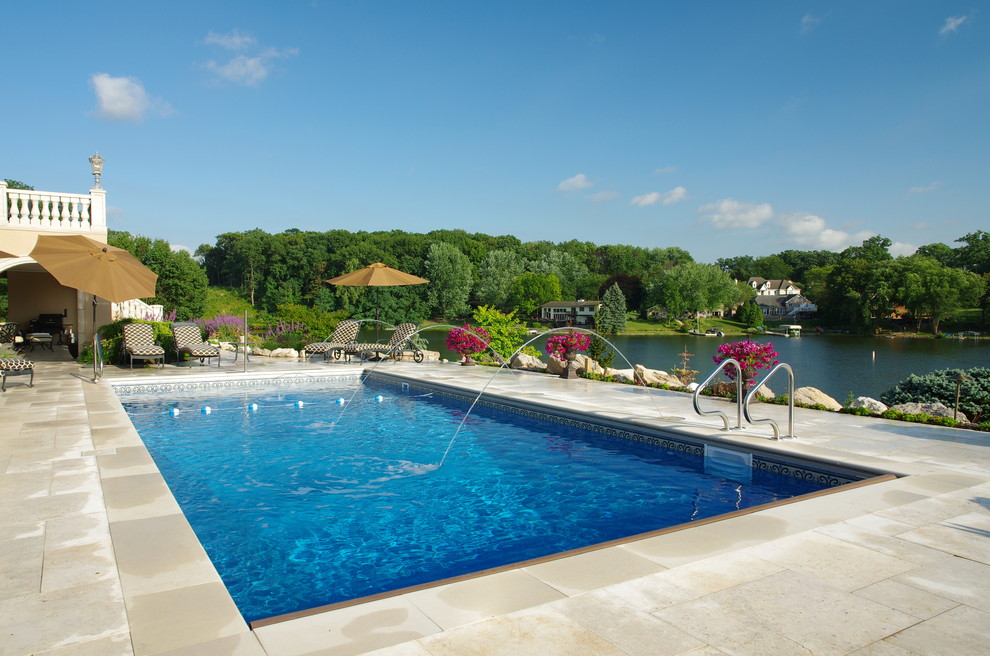 Foto di una grande piscina monocorsia minimalista rettangolare dietro casa con una vasca idromassaggio e pavimentazioni in pietra naturale