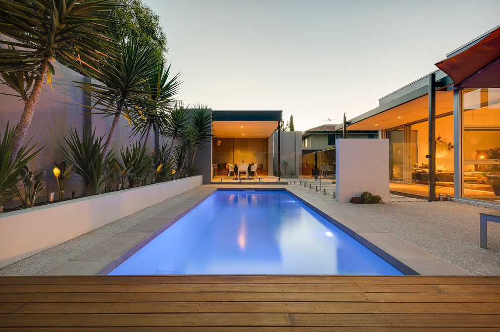 Inspiration pour une piscine arrière design de taille moyenne et rectangle avec une terrasse en bois.