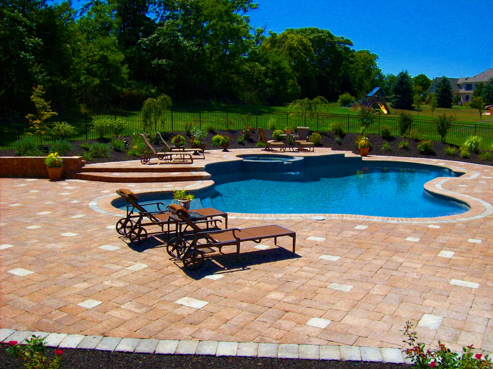 Example of a classic backyard concrete paver and custom-shaped hot tub design in Other