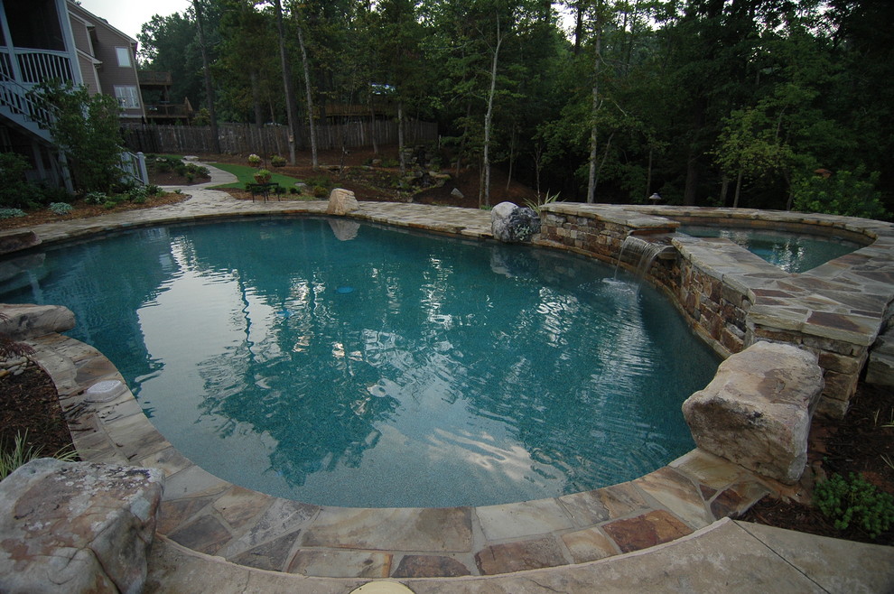 Immagine di una piscina rustica a "C" di medie dimensioni e dietro casa con una vasca idromassaggio e pavimentazioni in pietra naturale