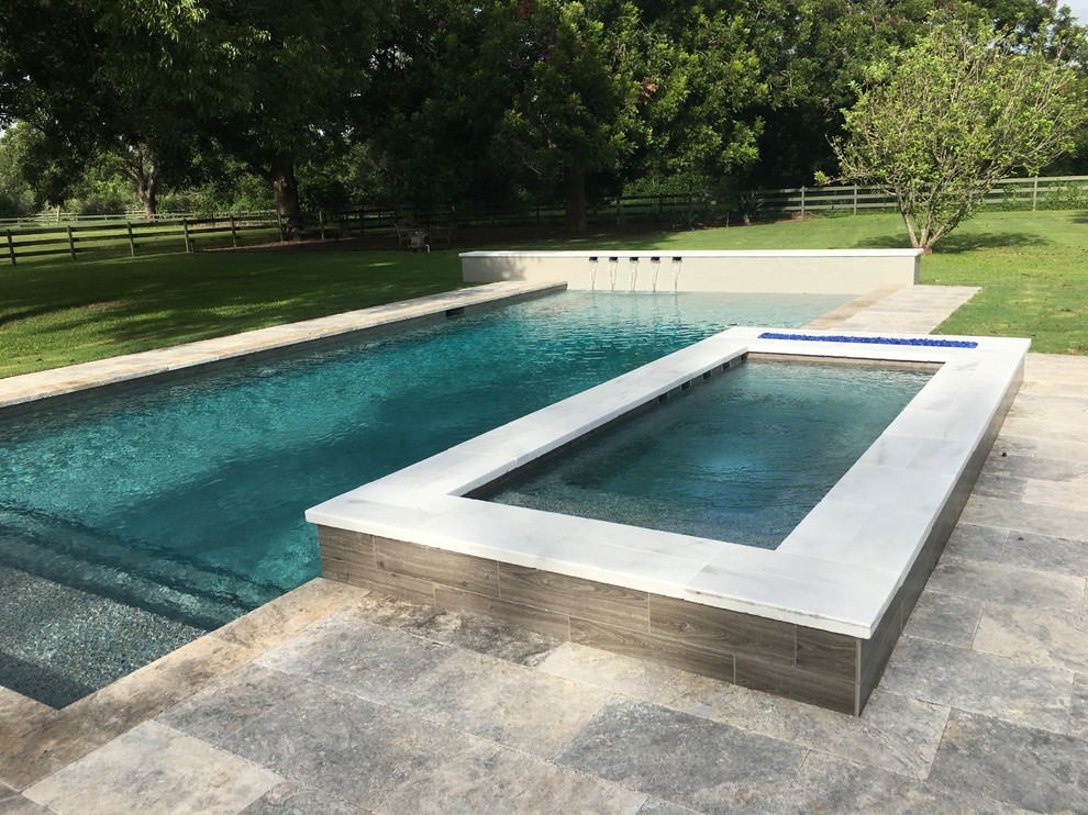 Idee per una grande piscina moderna rettangolare dietro casa con pavimentazioni in pietra naturale