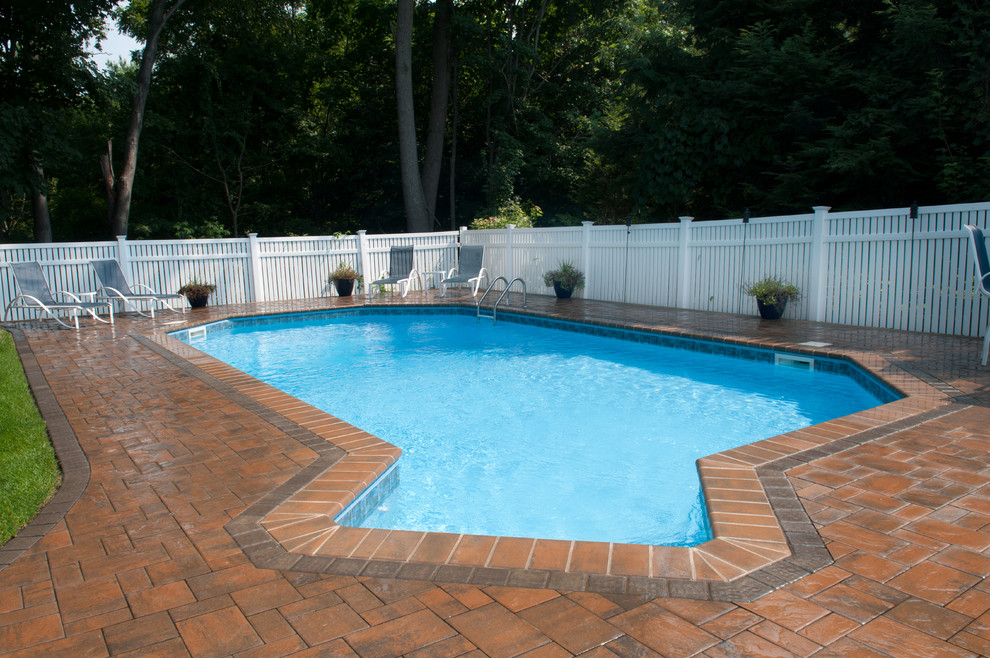 Exempel på en mellanstor klassisk anpassad pool på baksidan av huset, med marksten i betong