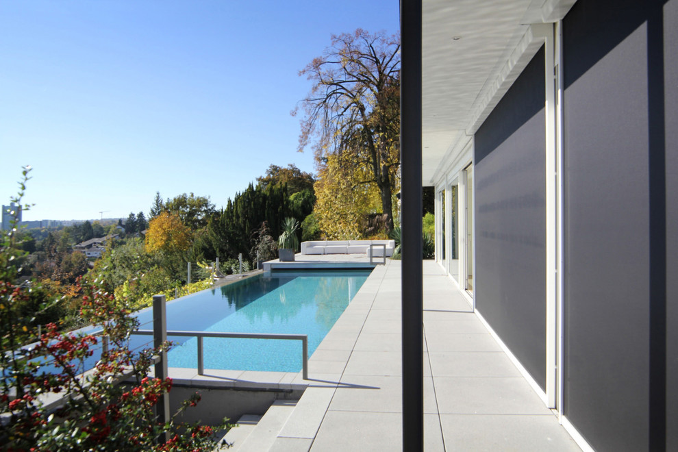 Großer Moderner Infinity-Pool hinter dem Haus in rechteckiger Form mit Betonplatten in Stuttgart