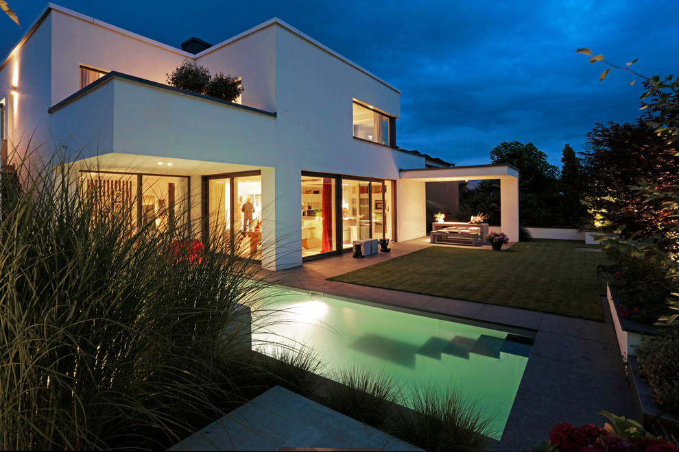 Ejemplo de piscina contemporánea de tamaño medio rectangular en patio trasero con adoquines de hormigón