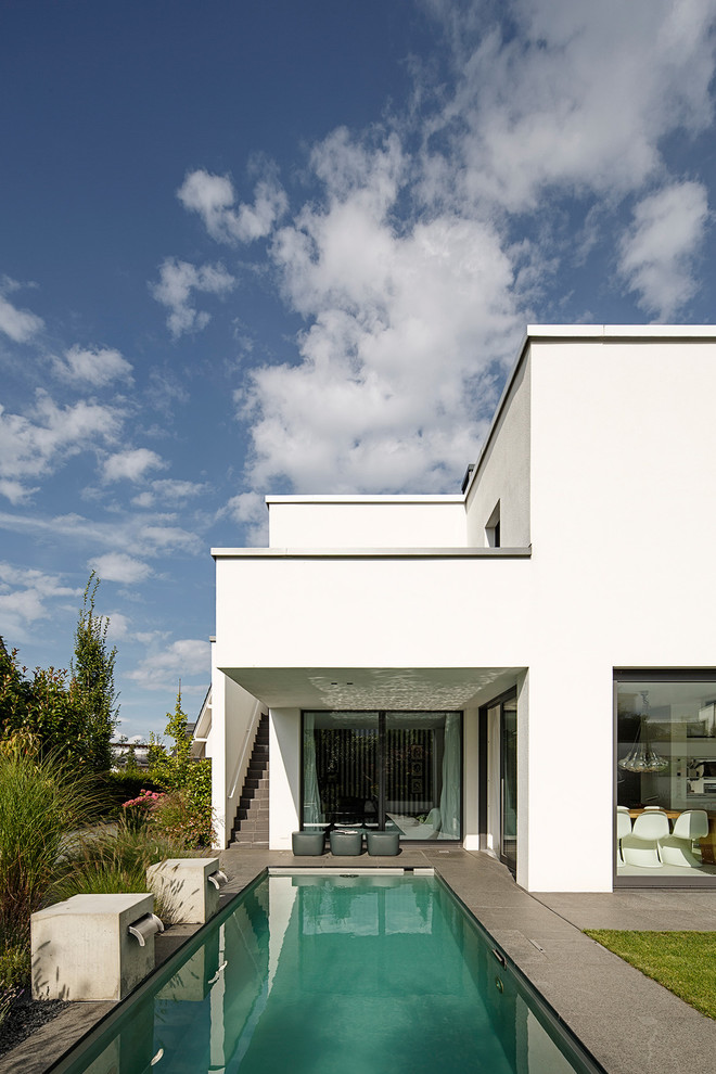 Esempio di una piscina monocorsia minimalista rettangolare di medie dimensioni e dietro casa con lastre di cemento