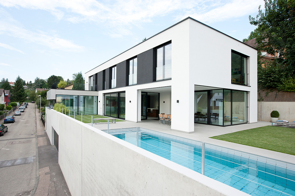 Photo of an expansive contemporary side rectangular lengths swimming pool in Other with concrete slabs.