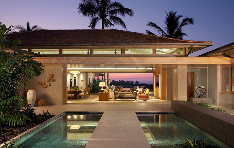 Diseño de piscina alargada tropical pequeña rectangular en patio trasero con losas de hormigón