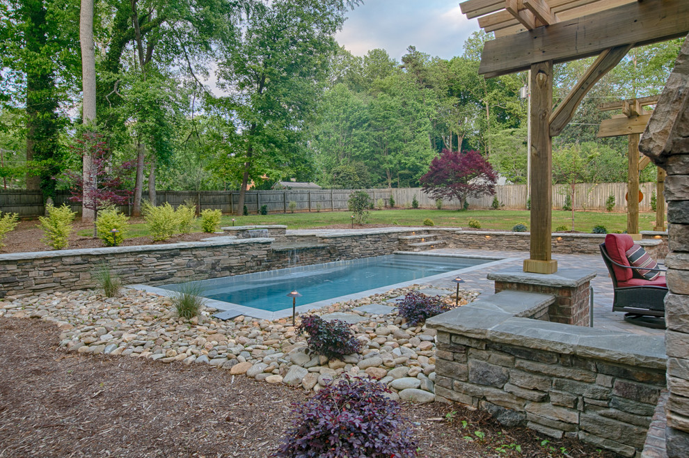 Imagen de piscina con fuente alargada de estilo americano de tamaño medio rectangular en patio trasero con adoquines de hormigón