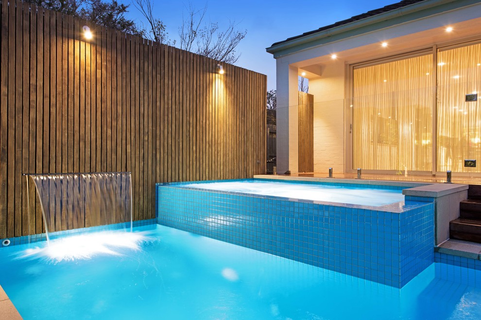 Medium sized modern back rectangular lengths swimming pool in Melbourne with a water feature and concrete paving.