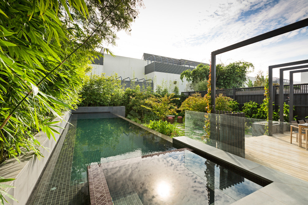 Foto de piscina infinita asiática de tamaño medio rectangular en patio trasero con suelo de baldosas