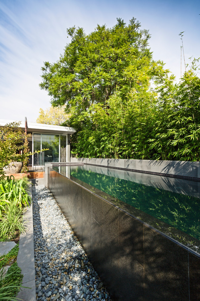 Esempio di una piscina a sfioro infinito etnica rettangolare di medie dimensioni e dietro casa con piastrelle