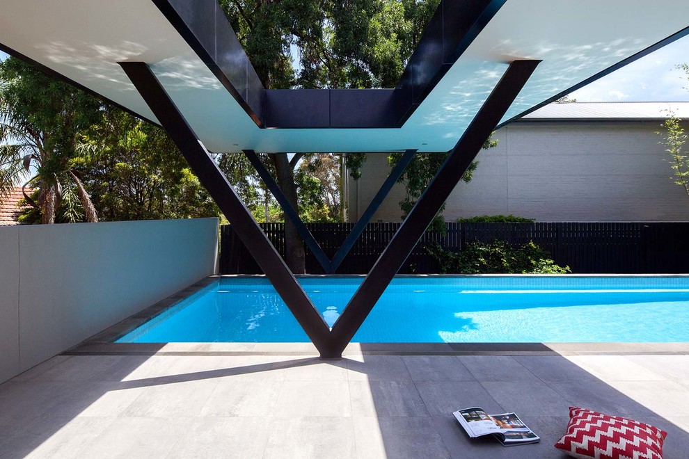 Immagine di una grande piscina monocorsia minimal rettangolare dietro casa con lastre di cemento