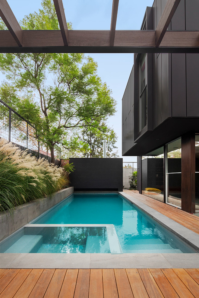 Стильный дизайн: прямоугольный бассейн на боковом дворе в современном стиле с настилом - последний тренд