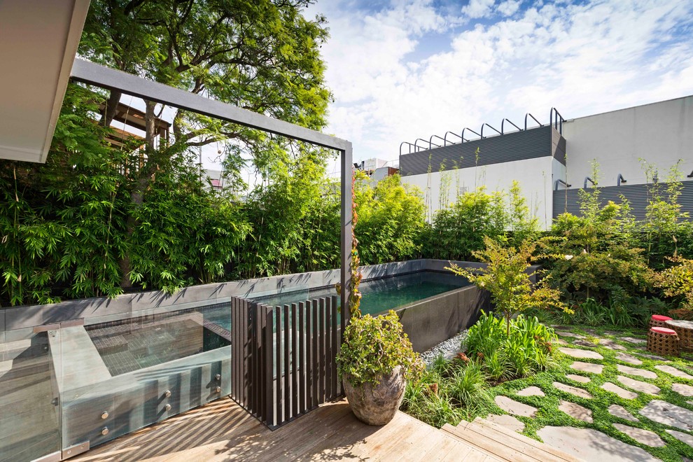 Idée de décoration pour une piscine arrière design de taille moyenne et rectangle avec une terrasse en bois.