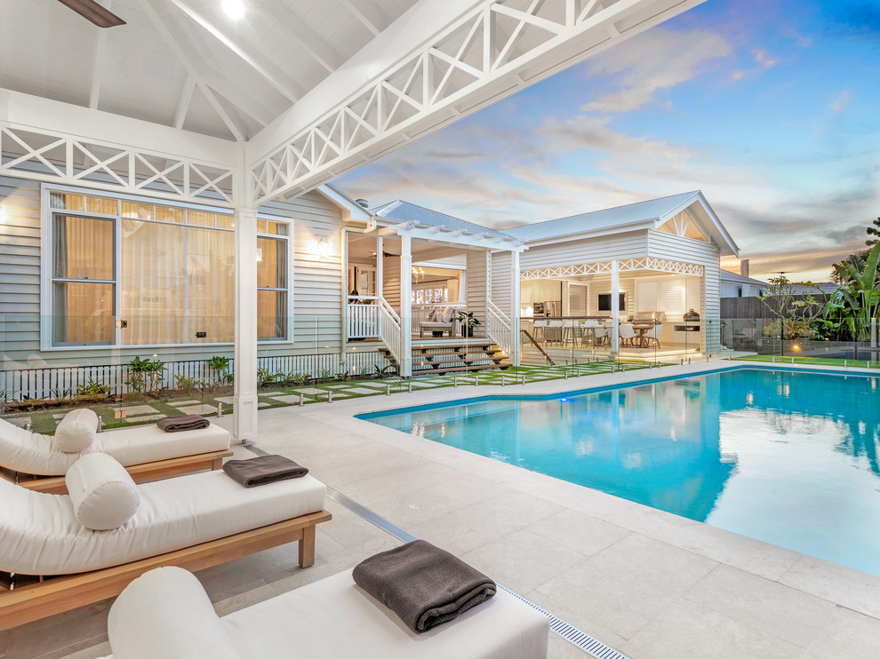 Ejemplo de casa de la piscina y piscina natural retro grande rectangular en patio trasero con adoquines de piedra natural
