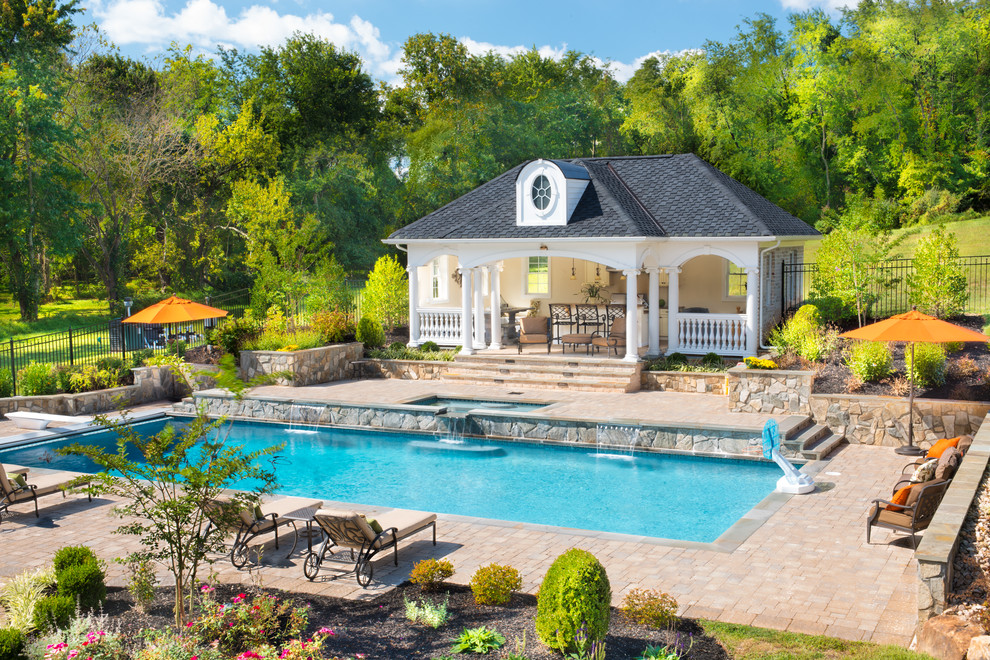 Foto på en stor vintage pool på baksidan av huset, med naturstensplattor och poolhus