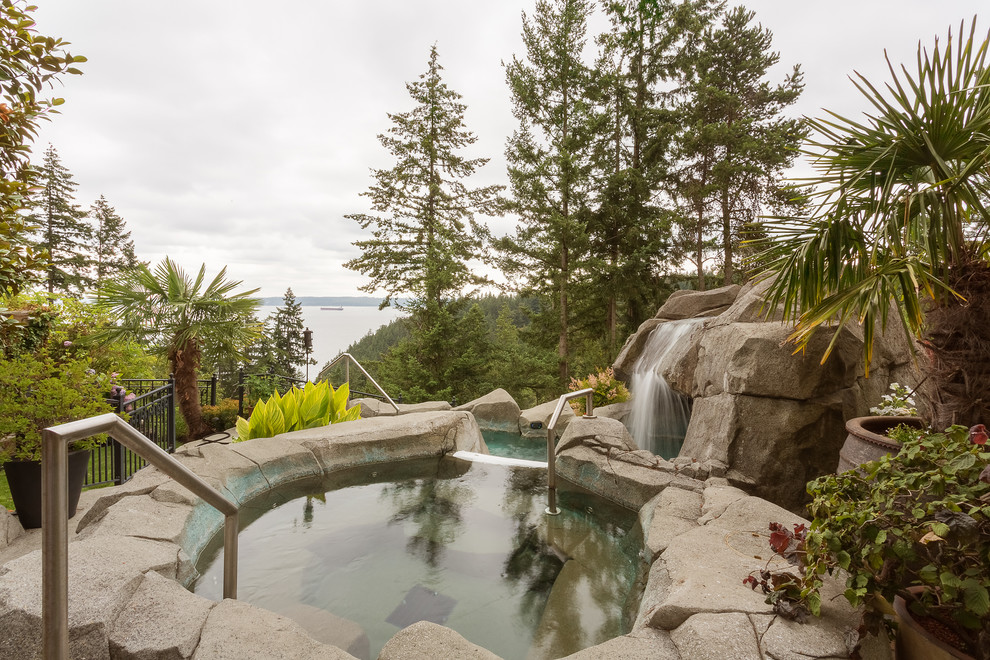Immagine di una piscina monocorsia classica personalizzata di medie dimensioni e dietro casa con pavimentazioni in pietra naturale e una vasca idromassaggio