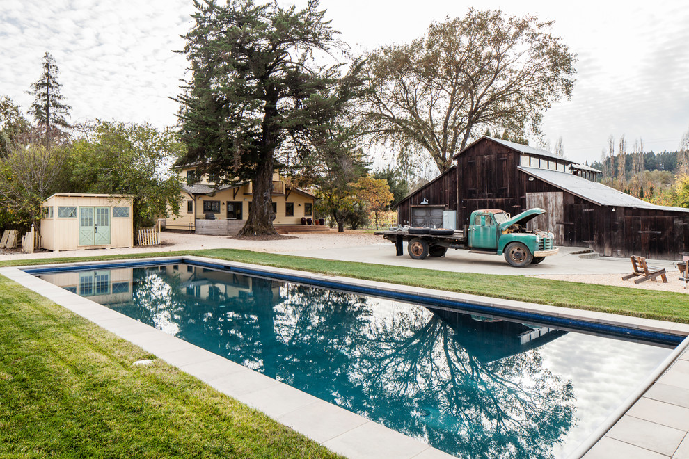 Diseño de piscina alargada de estilo americano de tamaño medio rectangular en patio trasero con adoquines de hormigón
