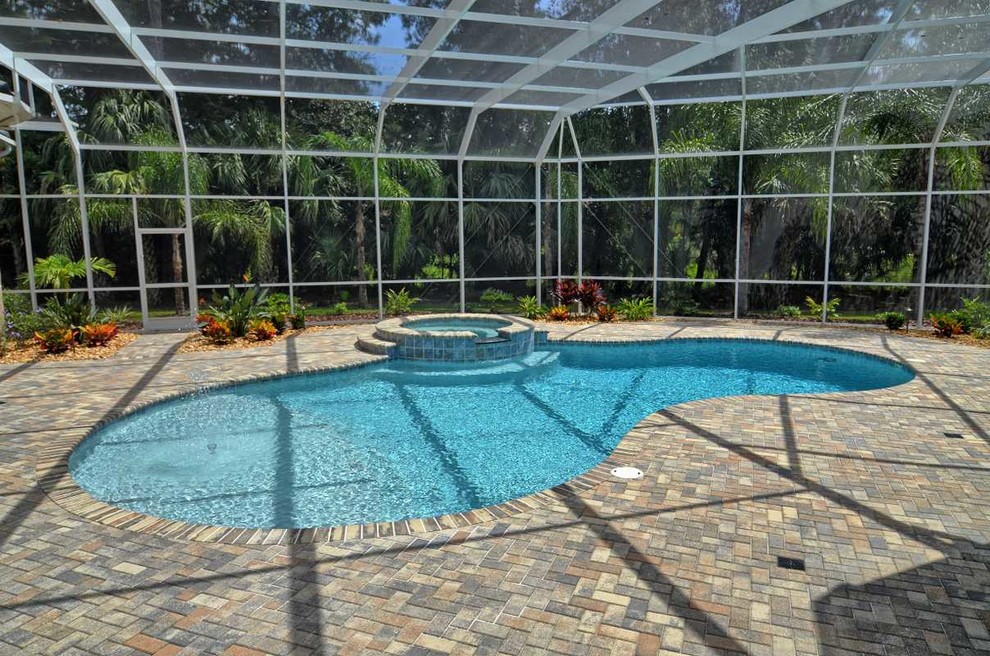 Diseño de casa de la piscina y piscina actual de tamaño medio tipo riñón en patio trasero con adoquines de ladrillo