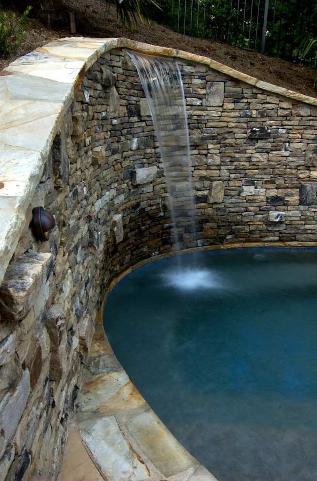 Aménagement d'une piscine naturelle et arrière montagne de taille moyenne et sur mesure avec un point d'eau et des pavés en brique.