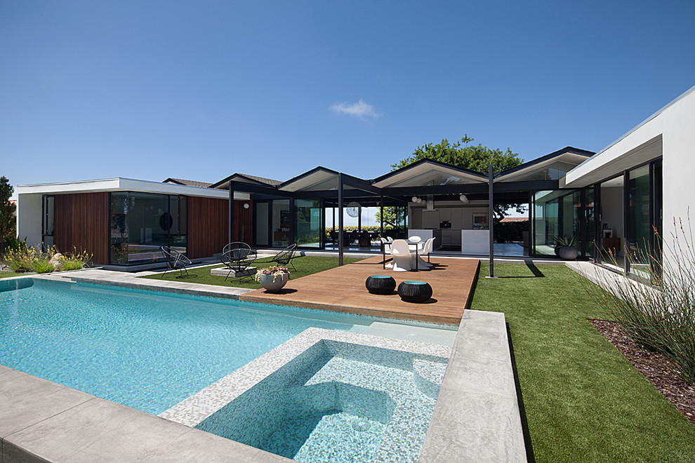 Diseño de piscina alargada minimalista de tamaño medio rectangular en patio trasero con losas de hormigón